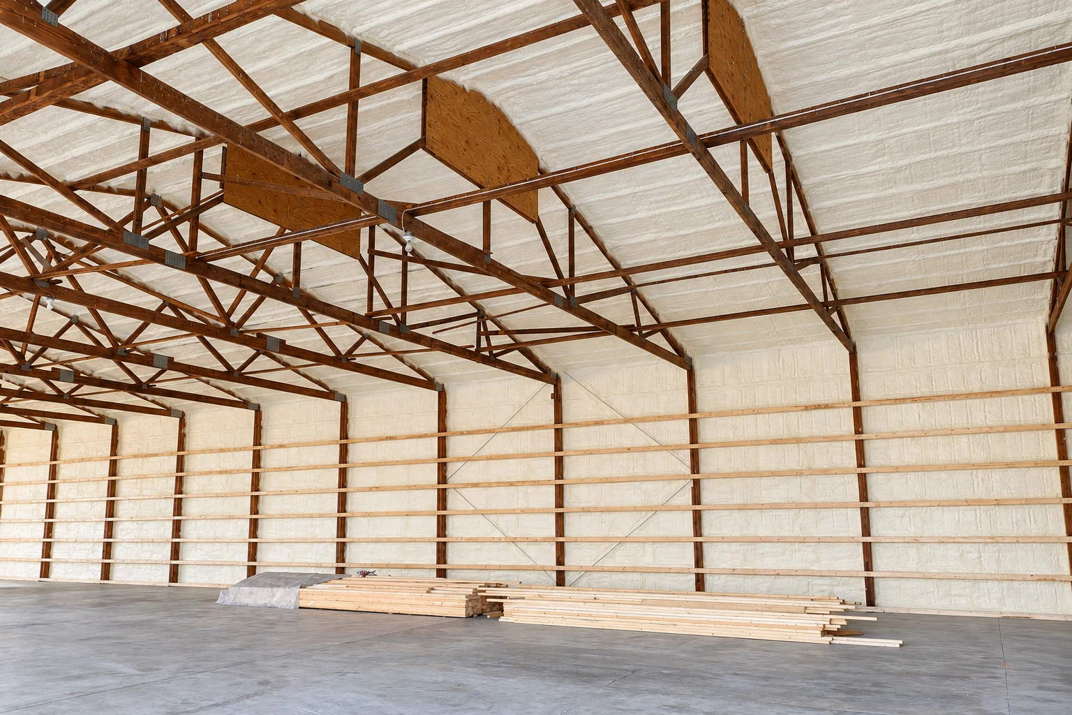 Large wooden-framed interior with white spray foam insulation covering the walls and roof panels.